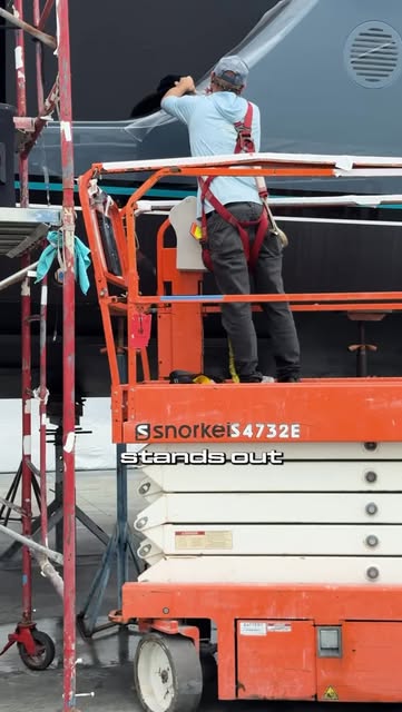 Global Yacht Detailing technician working from a lift alongside a superyacht hull